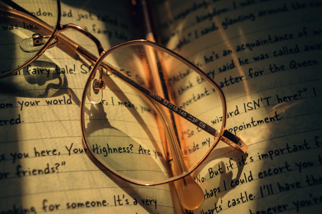 Home Vintage round spectacles rest on an open journal with handwritten notes.