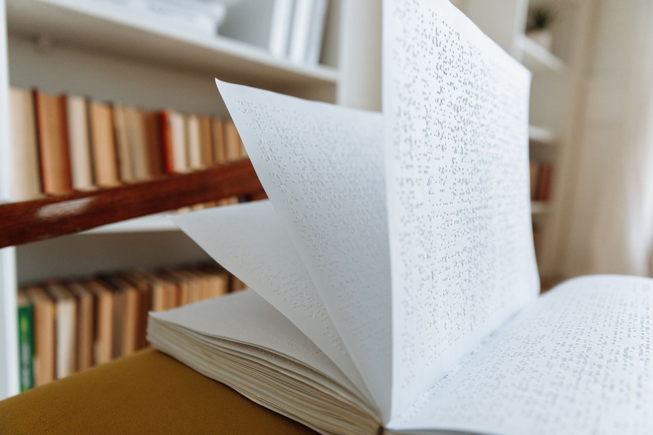 Home Close-up of an open braille book on a library table representing accessible reading.
